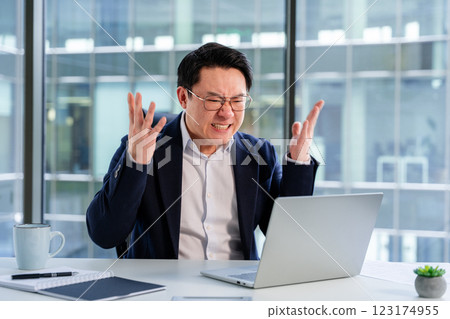 Stressed Businessman Expressing Frustration in Modern Office With Laptop Stressed Businessman Expressing Frustration in Modern Office With Laptop 123174955