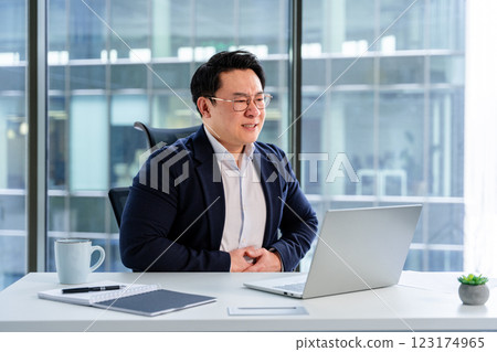 Professional Businessman Smiling During Virtual Meeting at Modern Office Professional Businessman Smiling During Virtual Meeting at Modern Office 123174965
