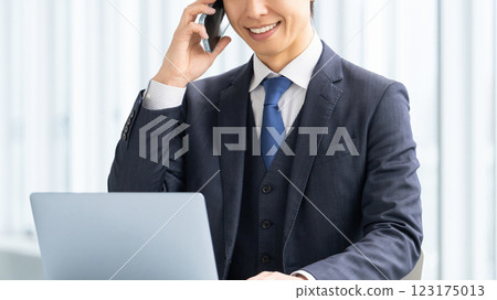 Smiling male businessman talking on a smartphone 123175013