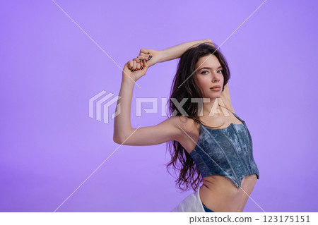 Model showcasing graceful pose against vibrant purple background Model showcasing graceful pose against vibrant purple background 123175151