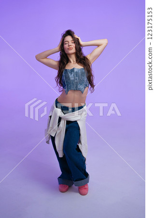 Model poses confidently in stylish outfit against purple background Model poses confidently in stylish outfit against purple background 123175153
