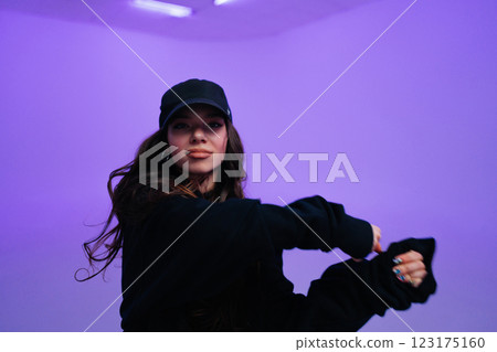 Young woman dancing in a stylish urban setting with purple lighting Young woman dancing in a stylish urban setting with purple lighting 123175160