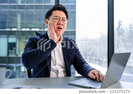 Asian Businessman Suffering Toothache While Working on Laptop in Office 123175173