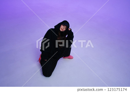 Young woman in casual streetwear poses on a colorful backdrop 123175174