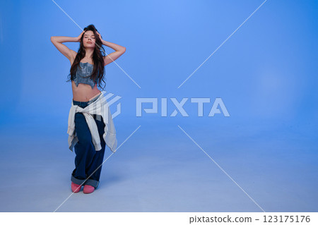Fashion model showcases trendy denim crop top and wide-leg pants in studio 123175176