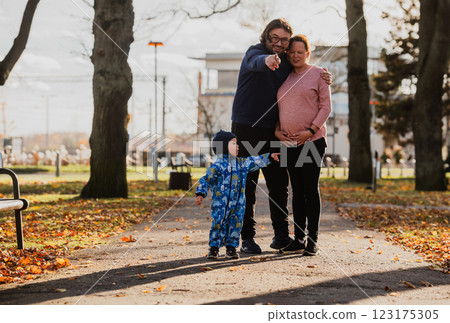 A loving couple strolls through a sunlit park with their young son, surrounded by the vibrant colors of autumn, enjoying a joyful and peaceful family moment together. A loving couple strolls through a sunlit park with their young son, surrounded by the vibrant colors of autumn, enjoying a joyful and peaceful family moment together. 123175305