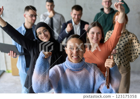 A diverse team of business professionals ecstatically celebrating their success in a modern office, expressing triumph and unity after achieving their goals 123175358