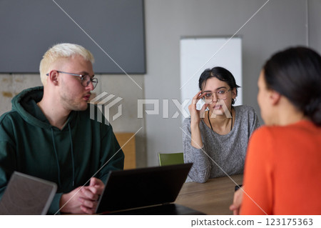 A young, diverse business team sitting together in a modern office, exchanging ideas and business plans, fostering collaboration and innovation for future success. 123175363