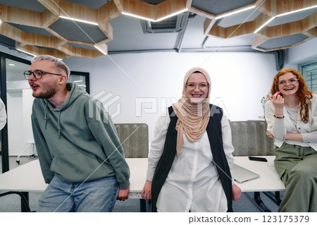 A group of young business professionals stands together, taking a well deserved break from their busy workday, showcasing camaraderie, teamwork, and a moment of relaxation in their dynamic workplace 123175379