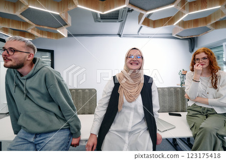 A group of young business professionals stands together, taking a well deserved break from their busy workday, showcasing camaraderie, teamwork, and a moment of relaxation in their dynamic workplace 123175418