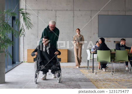 A diverse team of business colleagues, including a director in a wheelchair, engages in a collaborative discussion as they move together through a modern office space A diverse team of business colleagues, including a director in a wheelchair, engages in a collaborative discussion as they move together through a modern office space 123175477