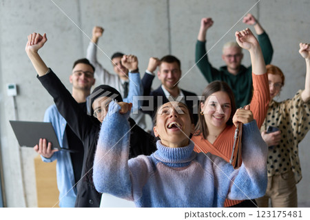 A diverse team of business professionals ecstatically celebrating their success in a modern office, expressing triumph and unity after achieving their goals A diverse team of business professionals ecstatically celebrating their success in a modern office, expressing triumph and unity after achieving their goals 123175481