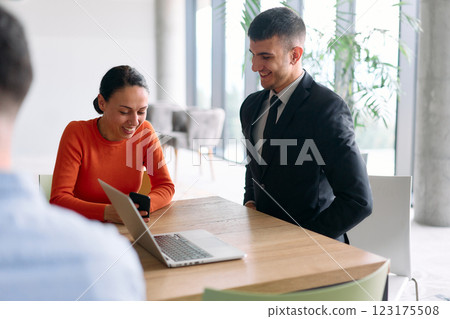 A young, diverse business team sitting together in a modern office, exchanging ideas and business plans, fostering collaboration and innovation for future success. 123175508