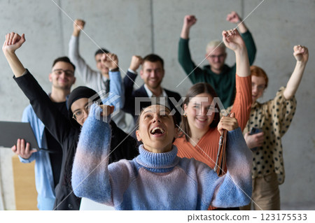 A diverse team of business professionals ecstatically celebrating their success in a modern office, expressing triumph and unity after achieving their goals A diverse team of business professionals ecstatically celebrating their success in a modern office, expressing triumph and unity after achieving their goals 123175533