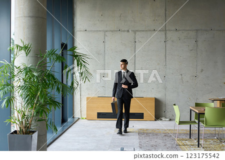 A determined businessman in a black suit confidently walks through the office, embodying professionalism and focus as he heads towards new challenges 123175542