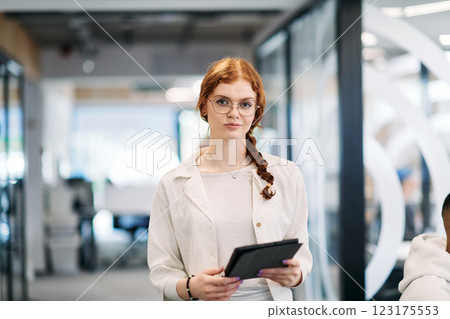 A business woman with orange hair self confident, fully engaged in working on a tablet, exuding creativity, ambition and a lively sense of individuality 123175553