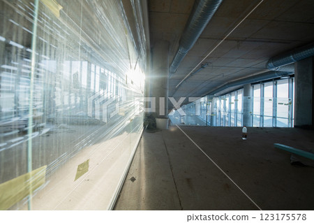 A captivating view of a modern business building under construction, showcasing its raw industrial interior with exposed steel beams and concrete walls bathed in the warm, golden hues of a sunset A captivating view of a modern business building under construction, showcasing its raw industrial interior with exposed steel beams and concrete walls bathed in the warm, golden hues of a sunset 123175578