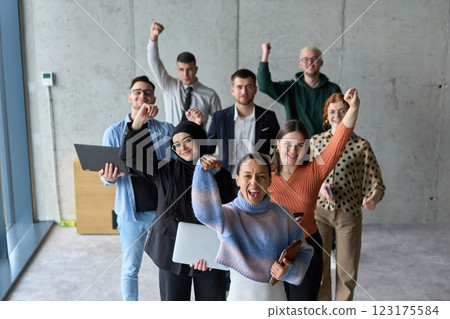 A diverse team of business professionals ecstatically celebrating their success in a modern office, expressing triumph and unity after achieving their goals 123175584