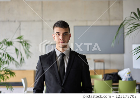 A close up portrait of a company director in a black suit, standing confidently in a modern office, exuding leadership, professionalism, and authority. A close up portrait of a company director in a black suit, standing confidently in a modern office, exuding leadership, professionalism, and authority. 123175702