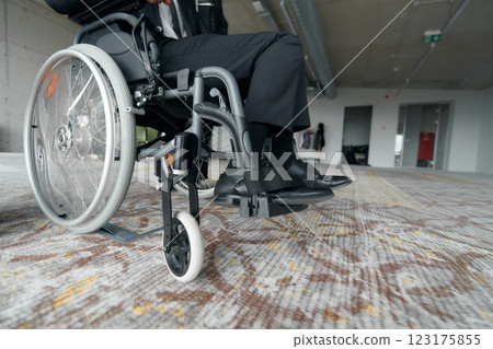 A businessman in a wheelchair enjoys a moment of laughter by a large window in a modern office, embodying positivity, resilience, and a balanced approach to work and life. A businessman in a wheelchair enjoys a moment of laughter by a large window in a modern office, embodying positivity, resilience, and a balanced approach to work and life. 123175855
