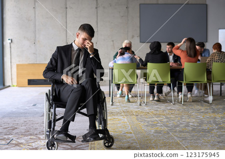 A sad and disheartened director in a wheelchair sitting alone in a large office, reflecting on the challenges and isolation that come with their professional responsibilities A sad and disheartened director in a wheelchair sitting alone in a large office, reflecting on the challenges and isolation that come with their professional responsibilities 123175945