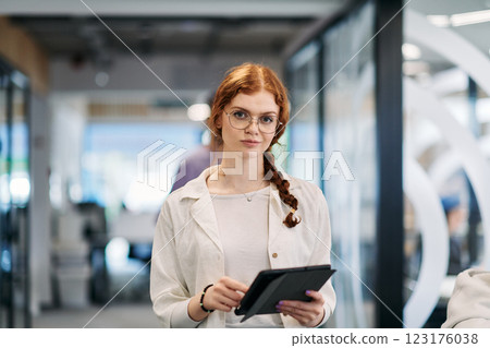 A business woman with orange hair self confident, fully engaged in working on a tablet, exuding creativity, ambition and a lively sense of individuality 123176038