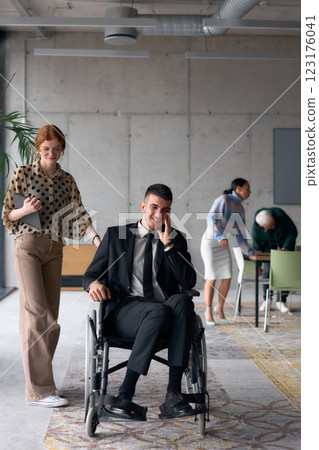Group cheerful business colleagues, including a businessman in a wheelchair, posing together in a modern office, showcasing teamwork and inclusivity 123176041