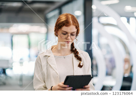 A business woman with orange hair self confident, fully engaged in working on a tablet, exuding creativity, ambition and a lively sense of individuality 123176064