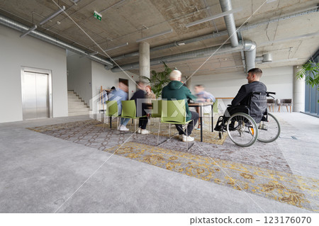 Business Team Led by Director in a Wheelchair Preparing for a Meeting in a Modern Office. 123176070