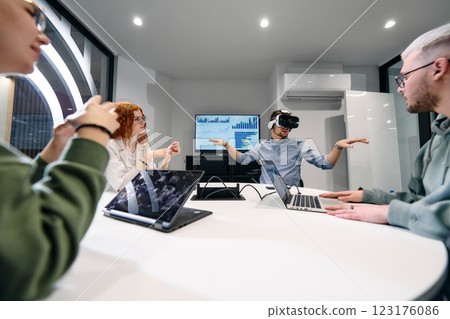 A diverse group of businessmen collaborates and tests a new virtual reality technology, wearing virtual glasses, showcasing innovation and creativity in their futuristic workspace 123176086