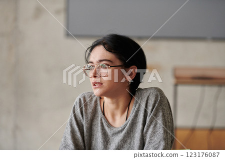 A close up portrait of a black haired businesswoman wearing glasses, captured while actively participating in a business meeting 123176087