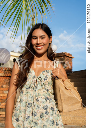 Young Asian woman holding bag outdoors during summer Young Asian woman holding bag outdoors during summer 123176180