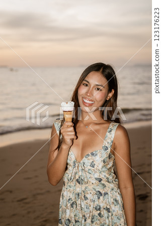 Young woman on the beach eating ice cream Young woman on the beach eating ice cream 123176223