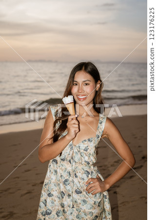 Young woman on the beach eating ice cream Young woman on the beach eating ice cream 123176225