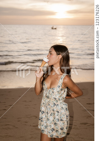 Young woman on the beach eating ice cream Young woman on the beach eating ice cream 123176226
