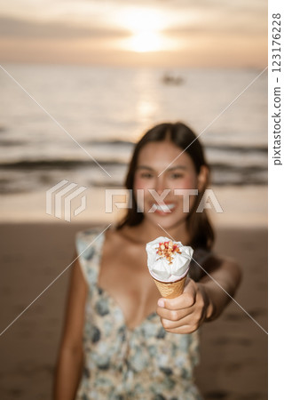 Young woman on the beach eating ice cream Young woman on the beach eating ice cream 123176228