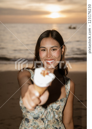 Young woman on the beach eating ice cream 123176230