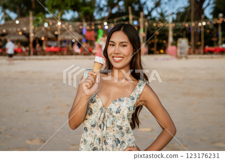 Young woman on the beach eating ice cream Young woman on the beach eating ice cream 123176231