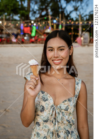 Young woman on the beach eating ice cream 123176234