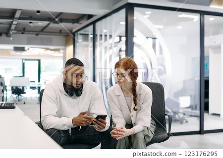 In a modern office African American businessman and businesswoman colleague, with her striking orange hair, engage in collaborative problem-solving sessions 123176295