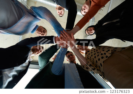 A group of business professionals, captured from a low angle, holding hands to symbolize unity and teamwork. 123176323