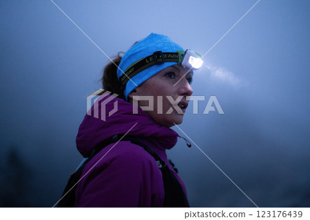 Determined Woman Trail Running at Night, Illuminated by a Headlamp in the Mountain Wilderness. 123176439