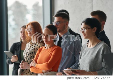 A group of accomplished business professionals stands together in an office, exuding unity, confidence, and a shared commitment to success and innovation. 123176456