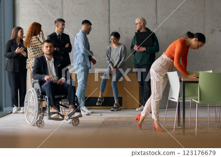 A diverse team of business professionals in a modern office stands alongside their director in a wheelchair, embodying inclusivity, collaboration, and leadership in the workplace A diverse team of business professionals in a modern office stands alongside their director in a wheelchair, embodying inclusivity, collaboration, and leadership in the workplace 123176679