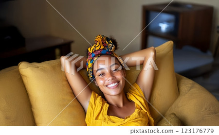 Young African woman with vitiligo smiling and relaxing on the sofa at home. Generated image 123176779
