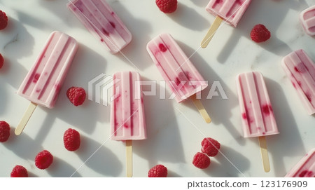 creamy raspberry yogurt popsicles with vibrant red fruit swirl, soft pink hue, arranged on white marble background, fresh raspberries scattered around 123176909