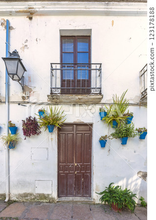The Calleja de las Flores, popular tourist street of Cordoba city in Andalusia, Spain. Whitewashed building with brown door, balcony, and blue flower pots. A charming, rustic scene. The Calleja de las Flores, popular tourist street of Cordoba city in Andalusia, Spain. Whitewashed building with brown door, balcony, and blue flower pots. A charming, rustic scene. 123178188