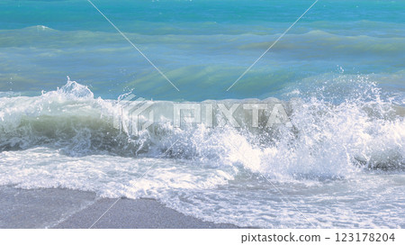 Nerja town, a resort of The Costa del Sol seaside region in Andalusia in the south of Spain. Ocean wave crashing on sandy beach, creating white foam and splashes. 123178204