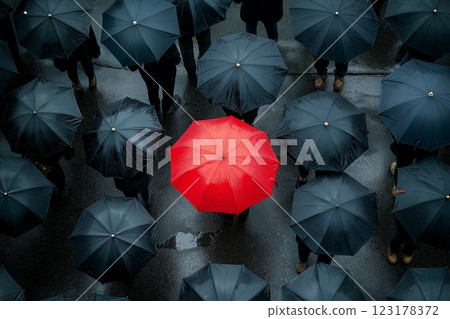 Crowded city street filled with umbrellas during a rainy day with one striking red umbrella in focus 123178372