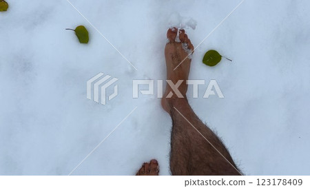Top view of male bare feet stepping on white snow. Legs of man going on snowy trail. Young guy hardening at cold winter. Concept of healthy lifestyle. POV Slow motion 123178409